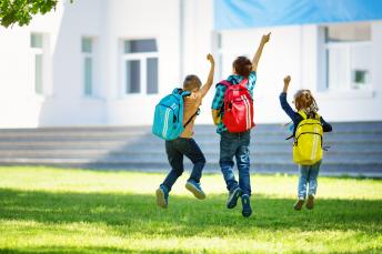 Drei Schüler von hinten, die in die Luft springen